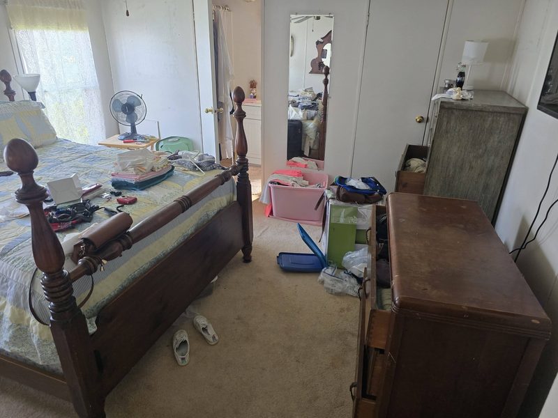 Bedroom with furniture, dressers and clothing being sorted